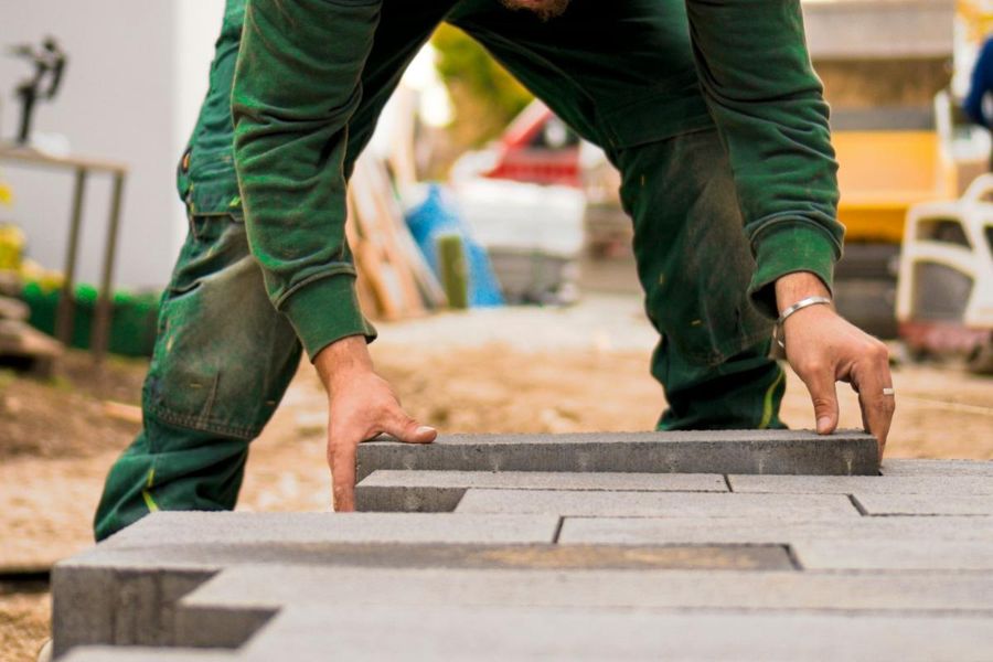 Crew member setting concrete pavers